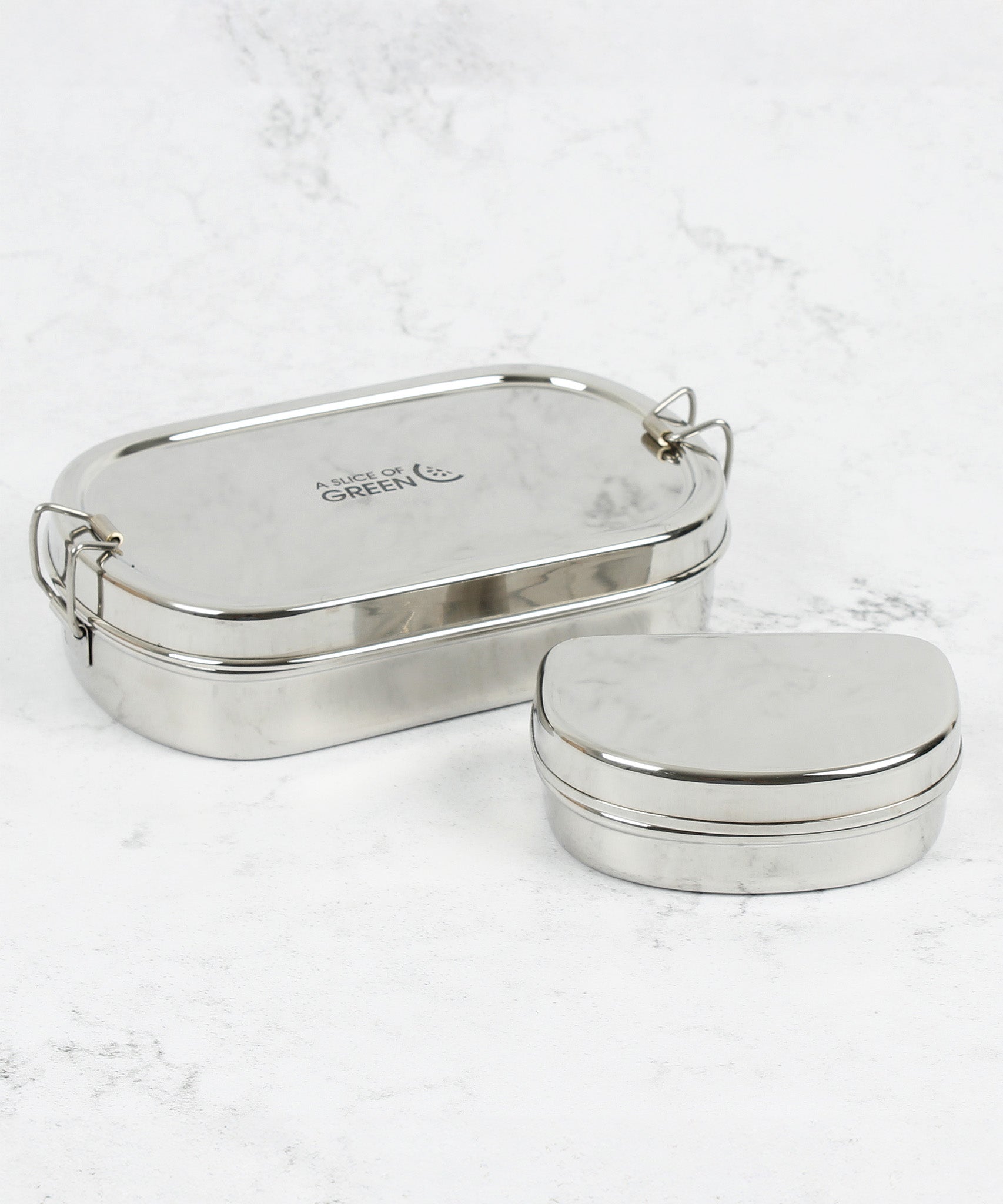 A slice of green oval lunchbox with mini container on a stone surface with clip fasteners available at Babipur.