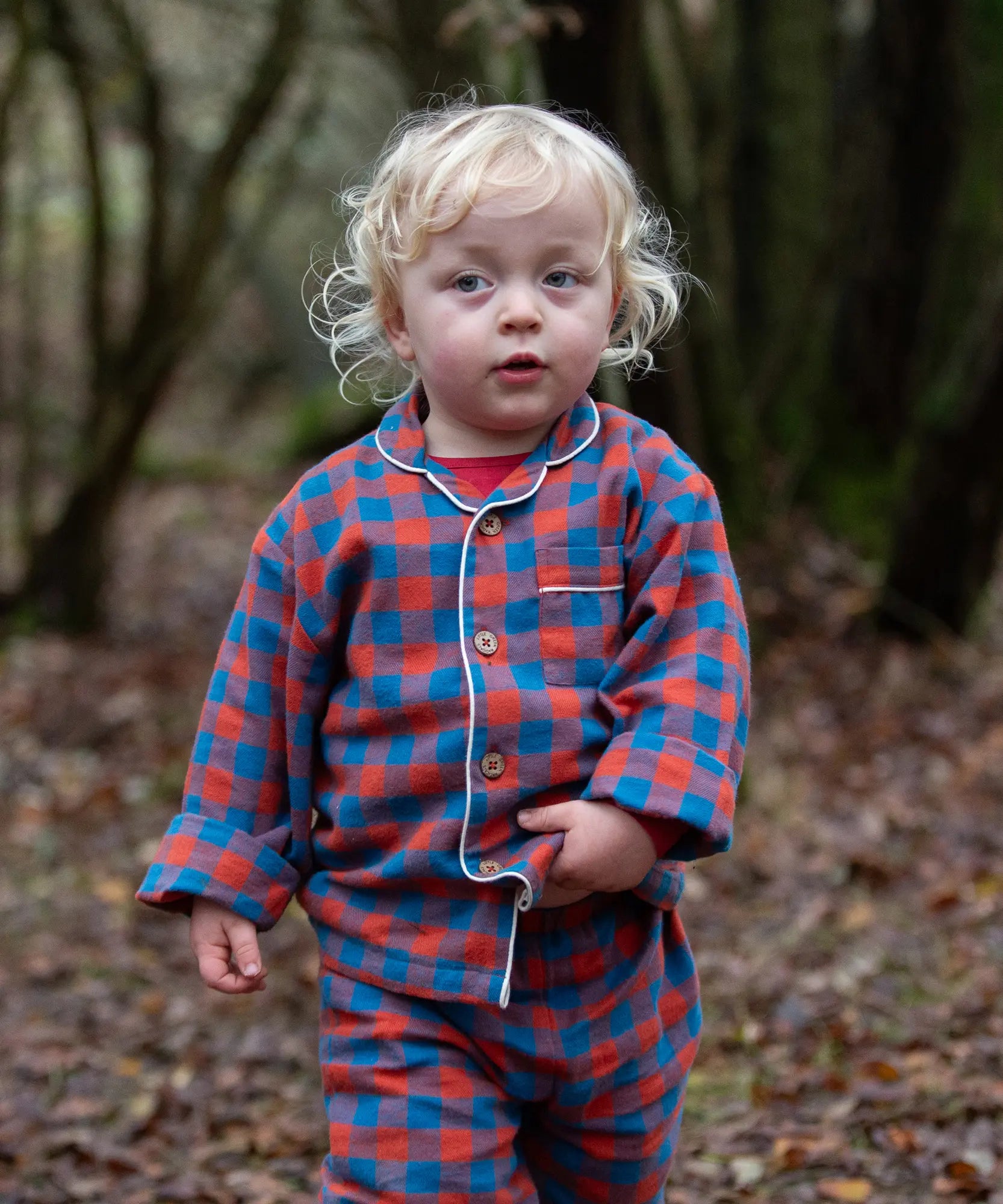 Child wearing the Little Green Radicals burnt ochre check classic pyjamas.