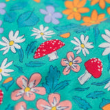 A super close up of the print on the Frugi Sofia skater dress with a wild woods print design on a green background. The print features flowers, toadstools and leaves.