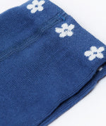A close up of the waist band on the Frugi Norah navy blue Flowers design footed tights. A navy waist band with little white flowers all around. 