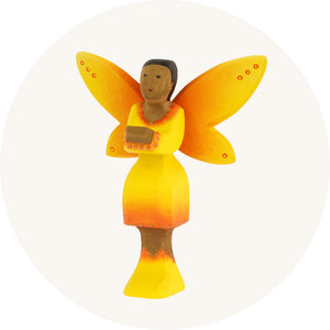 Bumbu Wooden Toy Fairy with a yellow and orange ombre dress, wings and shoes with brown skin and black hair, to represent all Bumbu toys for sale at Babipur, official UK stockist.