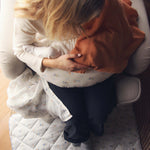 Avery Row Nursing Pillow - Coastline, a mother breastfeeding her baby with a brown muslin cover.