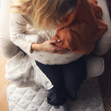 Avery Row Nursing Pillow - Coastline, a mother breastfeeding her baby with a brown muslin cover.