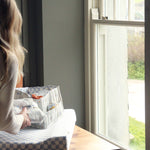 A person by a window, placing the Coastline Nappy Caddy on top of the Waves Changing Mat