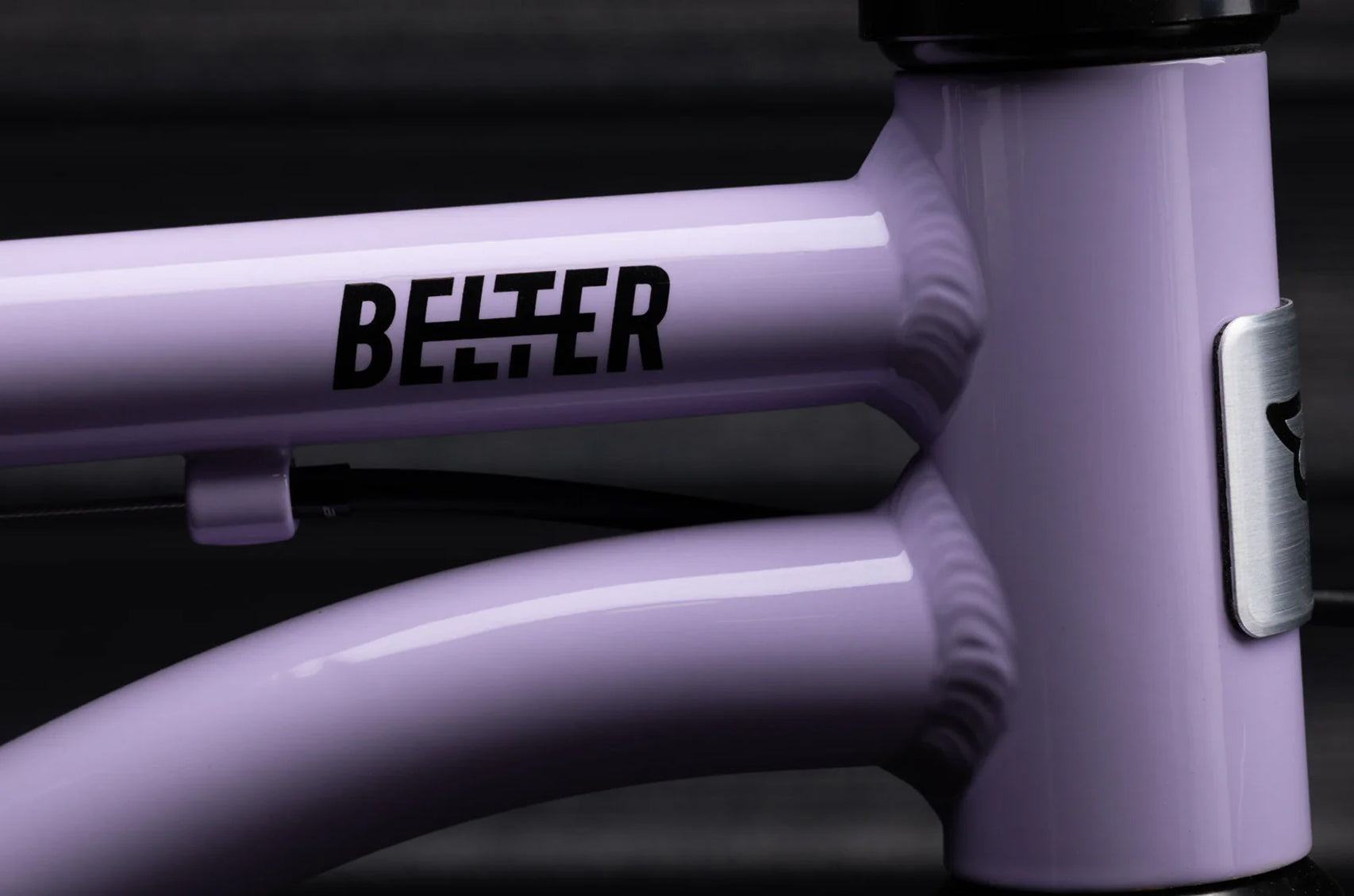Close-up of a purple bicycle frame in the color 'Violet Haze' with 'Belter' branding, on a dark background