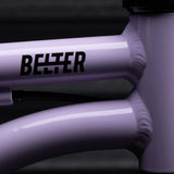 Close-up of a purple bicycle frame in the color 'Violet Haze' with 'Belter' branding, on a dark background