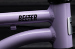 Close-up of a purple bicycle frame in the color 'Violet Haze' with 'Belter' branding, on a dark background