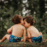 Two babies wearing The Close Pop-In x Babipur exclusive reusable nappy wrap, in a Babipur Dan y Ser print