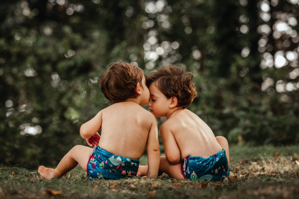 Two babies wearing The Close Pop-In x Babipur exclusive reusable nappy wrap, in a Babipur Dan y Ser print