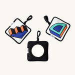 3 Etta Loves x Camille Walala Sensory Hanging Squares. The left square has a blue, black and orange steps print. The middle square is black with a small mirror in the centre. The right square has a blue, green and orange quarter of a circle shape.