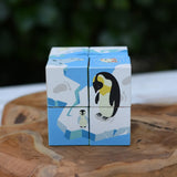 A 8-piece Bajo 2 in 1 cube wooden puzzle featuring penguin illustrations on a blue and white icy theme, displayed on a rustic wooden slice with a blurred green background.