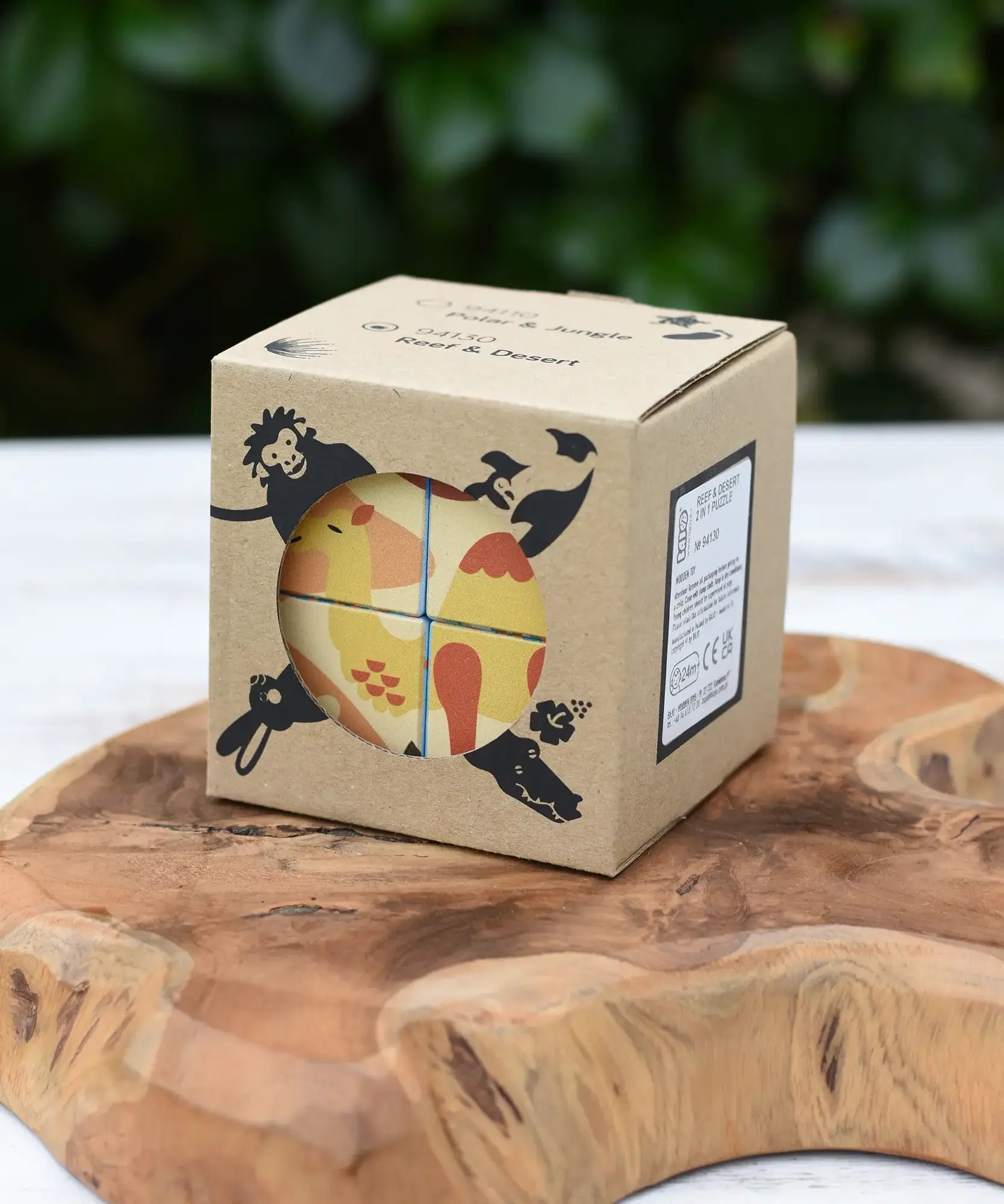 Bajo 2-in-1 reef desert wooden cube block puzzle shown in the cardboard packaging box placed on a wooden surface. 