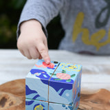 Child's hand pointing at the pink jelly fish on the Bajo 2-in-1 reef desert wooden cube block puzzle blocks. 