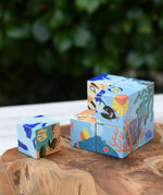 Bajo 2-in-1 reef desert wooden cube block puzzle shown on the reef design side with one block taken out of the cube.