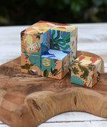 Bajo 2-in-1 reef desert wooden cube block puzzle, set of colorful, patterned wooden blocks with illustrated animal and nature designs, arranged on a rustic wooden board outdoors.
