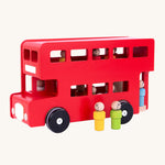 Another side view of the colourful peg dolls stood outside the bus, with other peg doll passengers and the peg doll driver inside, on a cream background
