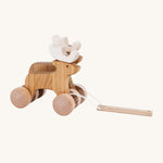 A side on view of the Bajo Pull Along Jumping Reindeer, showing the natural wood and white antlers of the reindeer. The image also shows how the two reindeer's are attached together by two wooden wheels. The mage is on a cream background