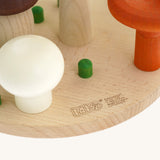 A close up of the Bajo wooden mushroom shape sorter available at Babipur showing the green peg detail and branding on the wooden circular base