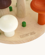 A close up of the Bajo wooden mushroom shape sorter available at Babipur showing the green peg detail and branding on the wooden circular base