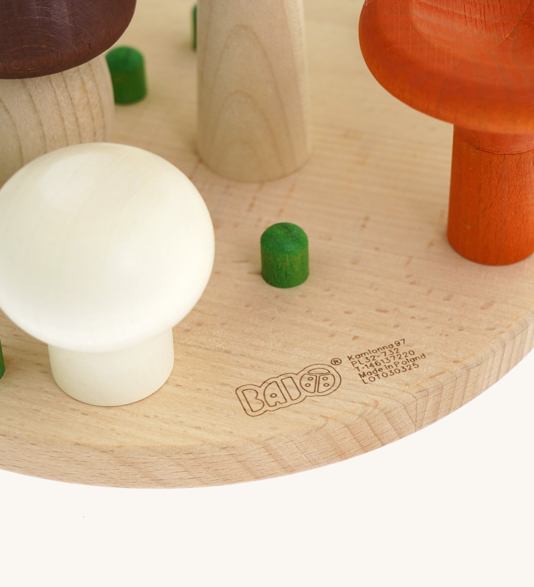 A close up of the Bajo wooden mushroom shape sorter available at Babipur showing the green peg detail and branding on the wooden circular base