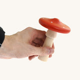 An adult hand holding the largest mushroom piece from the Bajo wooden mushroom shape sorter available at Babipur showing scale
