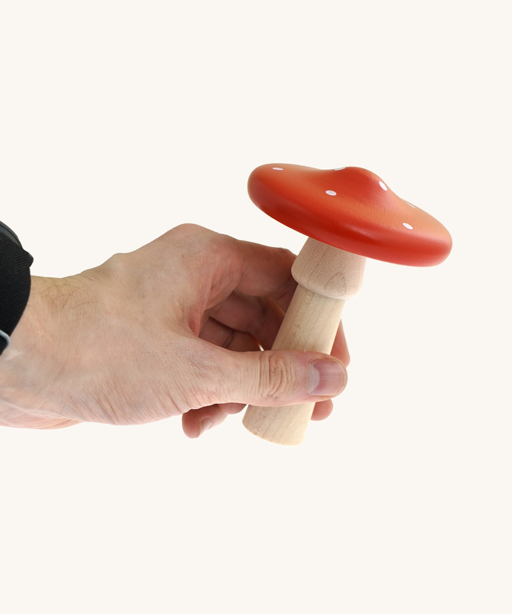An adult hand holding the largest mushroom piece from the Bajo wooden mushroom shape sorter available at Babipur showing scale