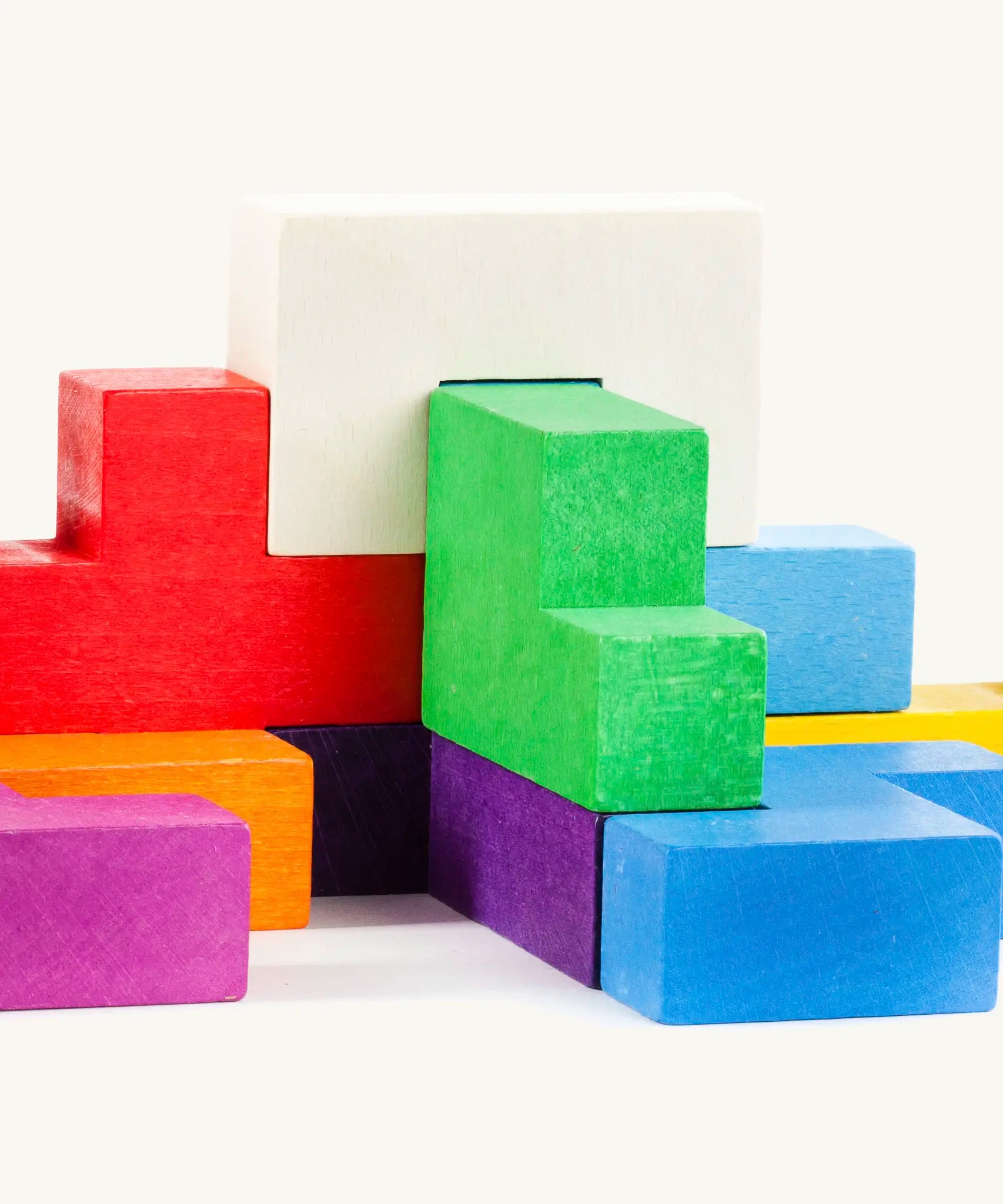 Different coloured wooden blocks from the Bajo Pentomino puzzle set stacked on top of each other