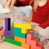 Child building a structure using different Bajo wooden coloured Pentomino puzzle blocks
