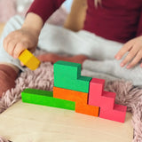 Child joining different Bajo wooden coloured Pentomino puzzle blocks on a wooden plate