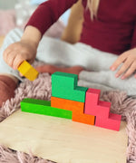 Child joining different Bajo wooden coloured Pentomino puzzle blocks on a wooden plate