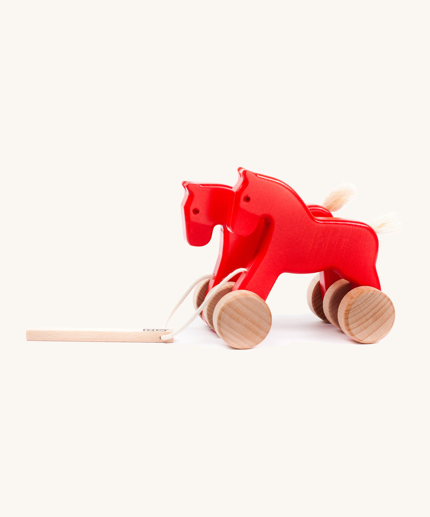 Bajo hand made wooden jumping horse in red and available at Babipur. Features unpainted wheels  and a toggle to pull along the horses
