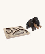 Bajo Puzzle & Sorter - Black Oak Mammoth which has been built and is stood next to it wooden puzzle tray, on a cream background