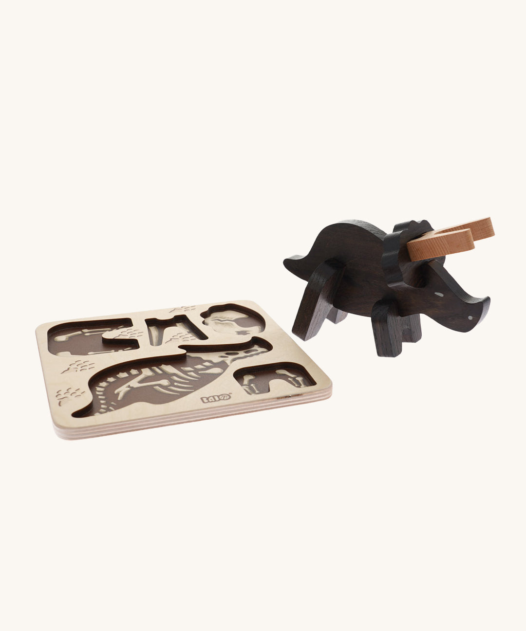 Bajo Puzzle & Sorter - Black Oak Triceratops which has been built and is stood next to its wooden puzzle board on a cream background
