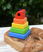 Bajo Puzzle Stacker Tower. A colorful wooden stacking toy set with five nested square blocks in blue, green, yellow, orange, and red, with a purple pole inside. 
