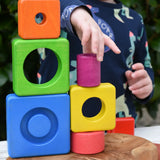 Child stacking colorful wooden blocks from the Bajo Puzzle Stacker Tower on top of each other.