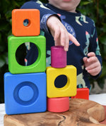 Child stacking colorful wooden blocks from the Bajo Puzzle Stacker Tower on top of each other.