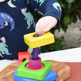 Child stacking the pieces from the Bajo Puzzle Stacker Tower onto the purple pole.