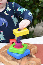 Child stacking the pieces from the Bajo Puzzle Stacker Tower onto the purple pole.