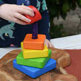 Child's hand placing the top red coloured block onto the top pf the Bajo Puzzle Stacker Tower.