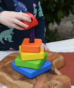 Child's hand placing the top red coloured block onto the top pf the Bajo Puzzle Stacker Tower.