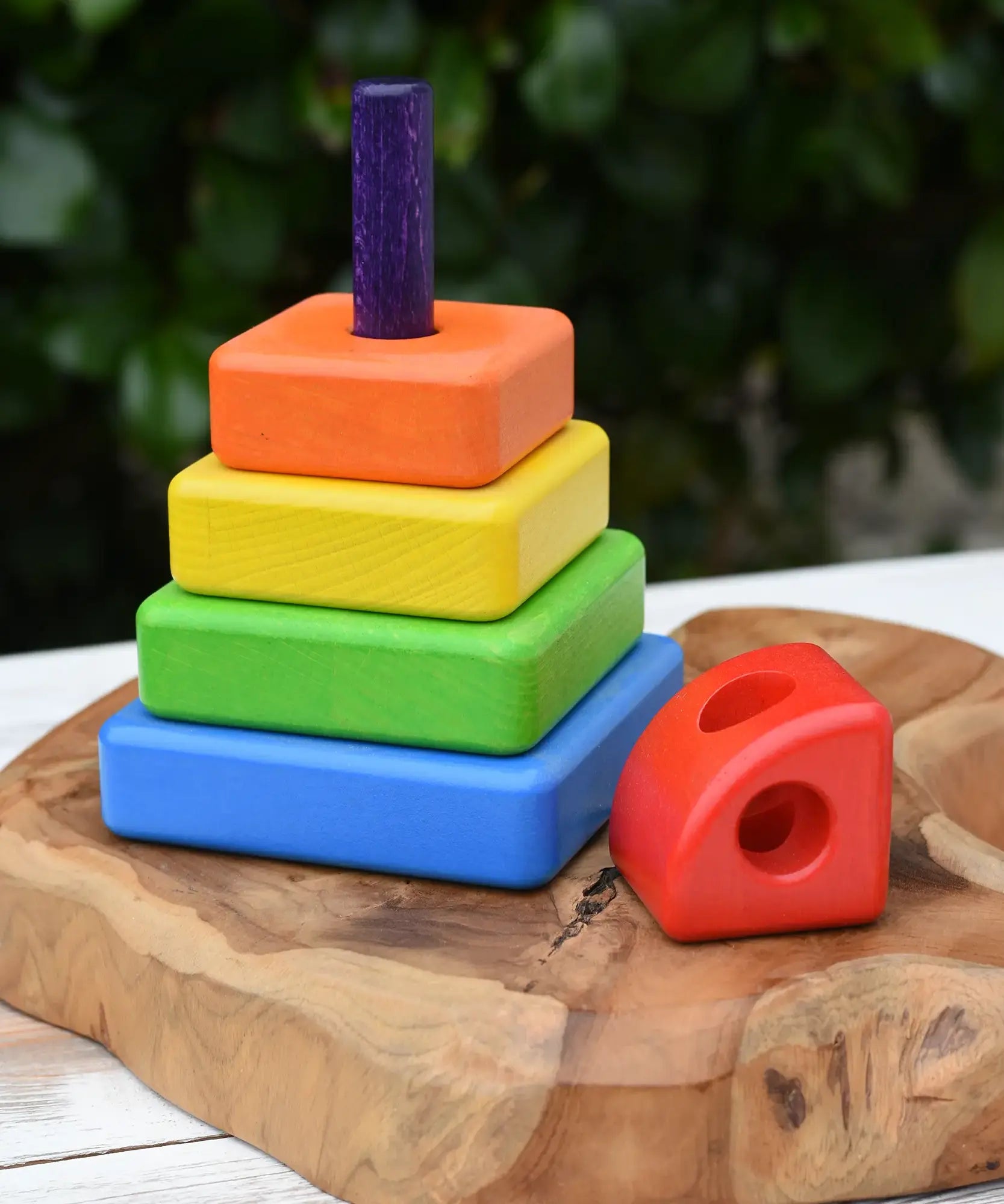 Bajo Puzzle Stacker Tower on a wooden base piece with the top red pieces placed besides it.