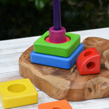 Bajo Puzzle Stacker Tower placed on a  wooden base with some of the pieces placed around the pole and base.