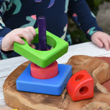 Child placing the pieces from the Bajo Puzzle Stacker Tower on the purple pole.