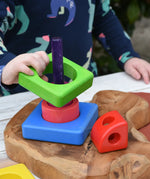Child placing the pieces from the Bajo Puzzle Stacker Tower on the purple pole.