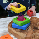 Child's hands are shown playing with a colorful wooden nesting shape-sorting toy from the Bajo Puzzle Stacker Tower.