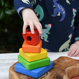 Child's hand stacks the pieces from the Bajo Puzzle Stacker Tower.