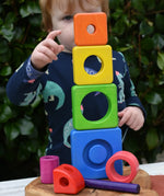 Child stacking the pieces from the Bajo Puzzle Stacker Tower on top of each other.