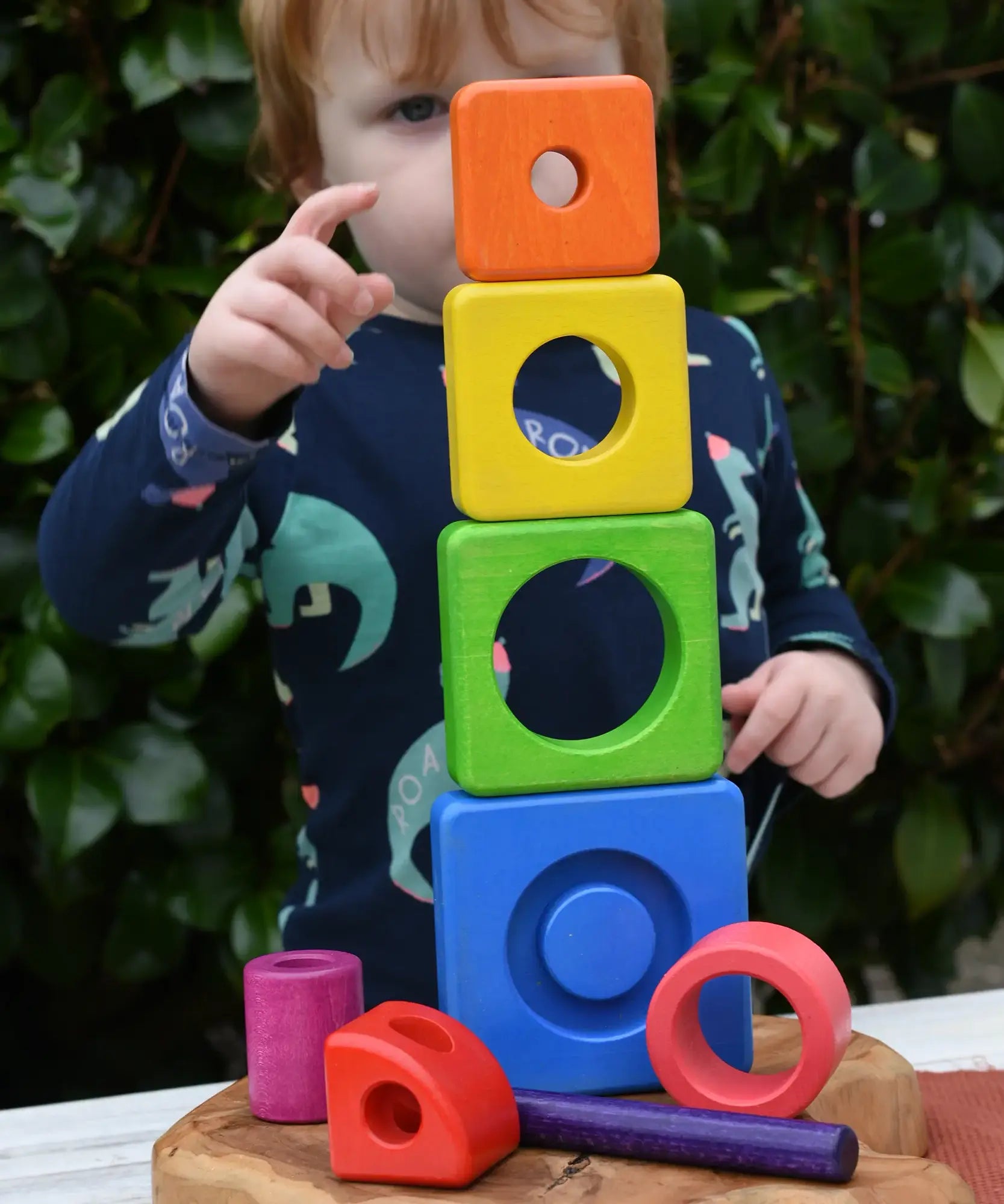 Child stacking the pieces from the Bajo Puzzle Stacker Tower on top of each other.