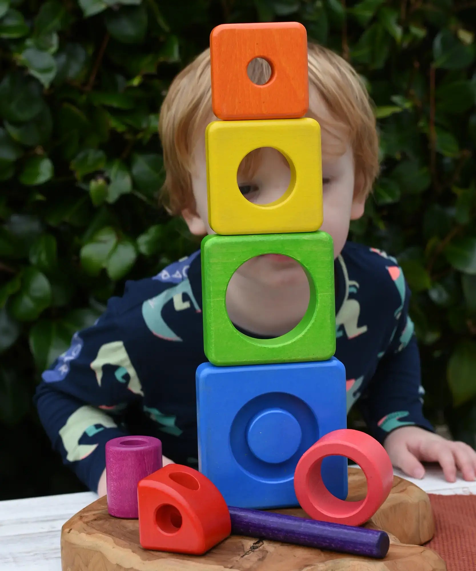 Child peering through stacked blocks from the Bajo Puzzle Stacker Tower.