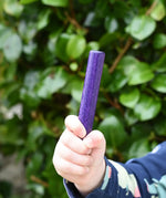 Child holding the purple pole from the Bajo Puzzle Stacker Tower in his hand. 